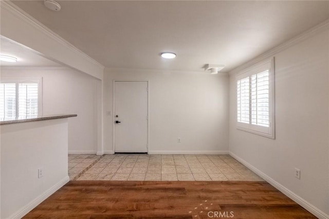 empty room featuring tile patterned flooring, plenty of natural light, and crown molding