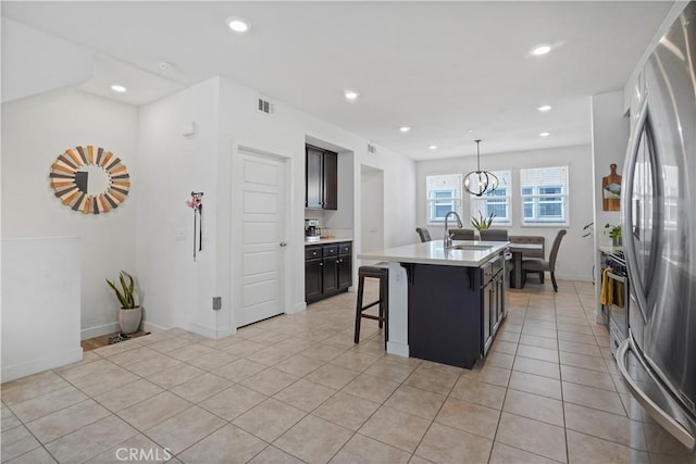 kitchen with sink, stainless steel appliances, a breakfast bar area, a kitchen island with sink, and light tile patterned flooring