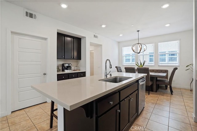 kitchen with a center island with sink, sink, hanging light fixtures, stainless steel dishwasher, and a breakfast bar area