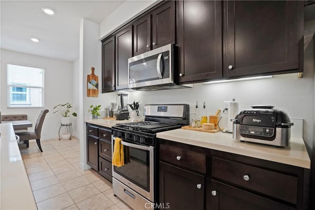 kitchen with light tile patterned floors, dark brown cabinetry, and appliances with stainless steel finishes