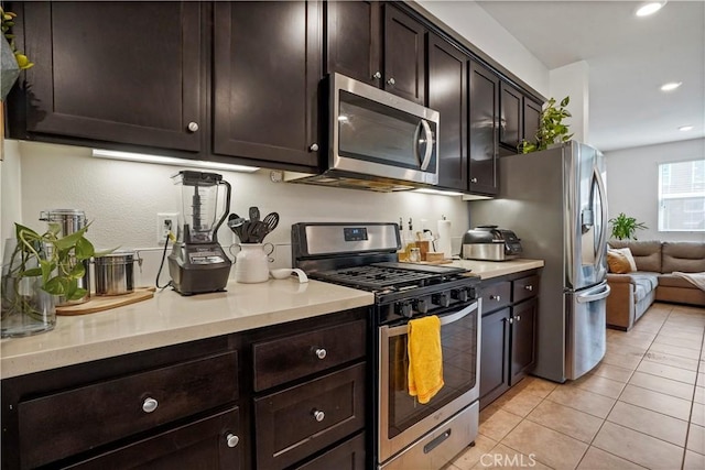 kitchen with light tile patterned floors, dark brown cabinetry, and stainless steel appliances