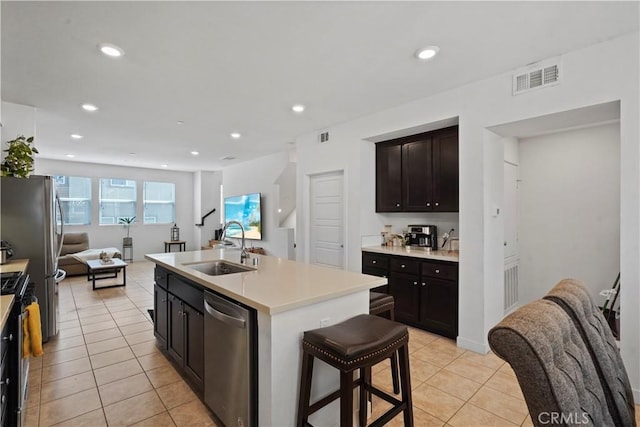 kitchen featuring sink, stainless steel appliances, an island with sink, a breakfast bar, and light tile patterned flooring