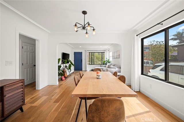 dining space featuring a notable chandelier, light hardwood / wood-style flooring, and crown molding