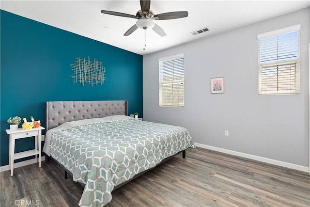 bedroom featuring ceiling fan, hardwood / wood-style flooring, and multiple windows