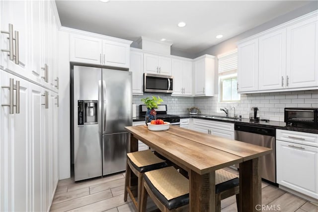 kitchen with white cabinets, backsplash, sink, and stainless steel appliances