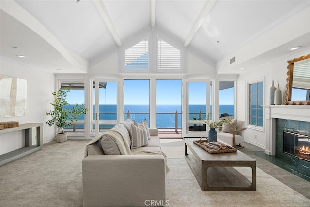 carpeted living room with a high end fireplace, beamed ceiling, a water view, and a healthy amount of sunlight