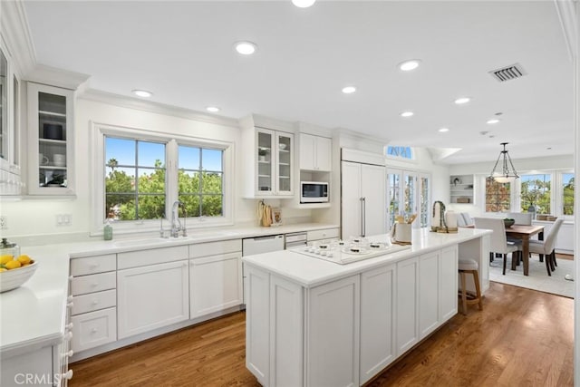 kitchen with a center island with sink, dark hardwood / wood-style flooring, a healthy amount of sunlight, and built in appliances