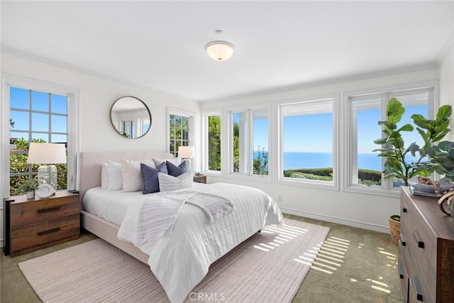 bedroom featuring ornamental molding, a water view, and light colored carpet