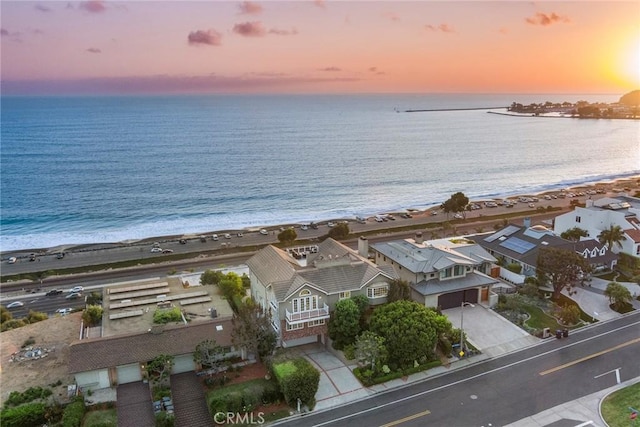 aerial view at dusk with a water view and a view of the beach