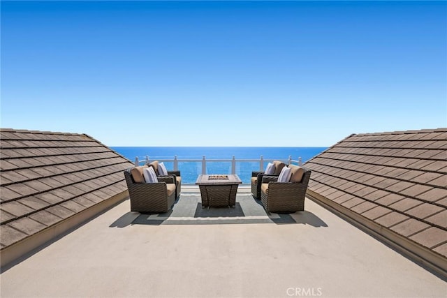 view of patio with a water view and an outdoor living space with a fire pit