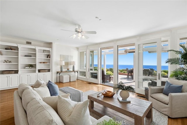 living room with light wood-type flooring, a water view, and a wealth of natural light