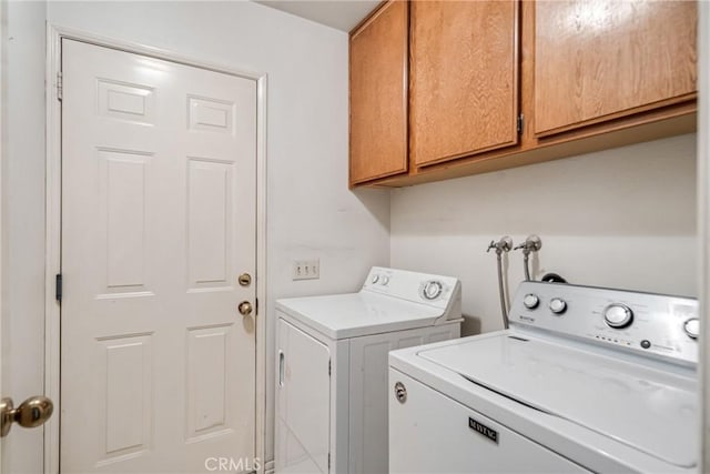 washroom featuring washing machine and clothes dryer and cabinets