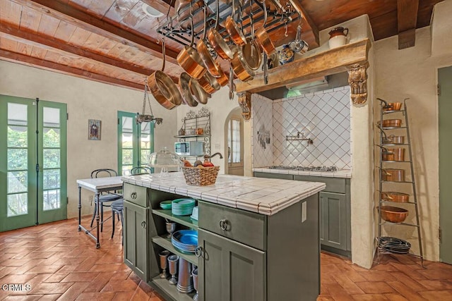 kitchen with tile countertops, backsplash, french doors, a kitchen island, and wood ceiling