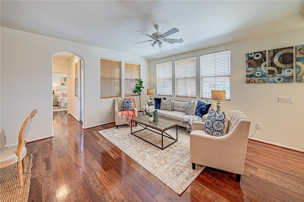 living room featuring ceiling fan and dark wood-type flooring