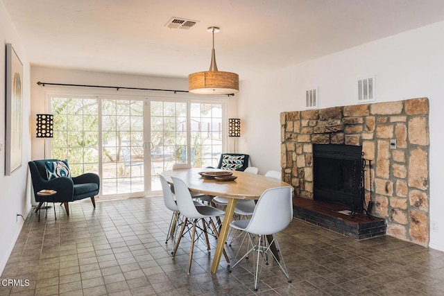 dining room with a fireplace and dark tile patterned flooring