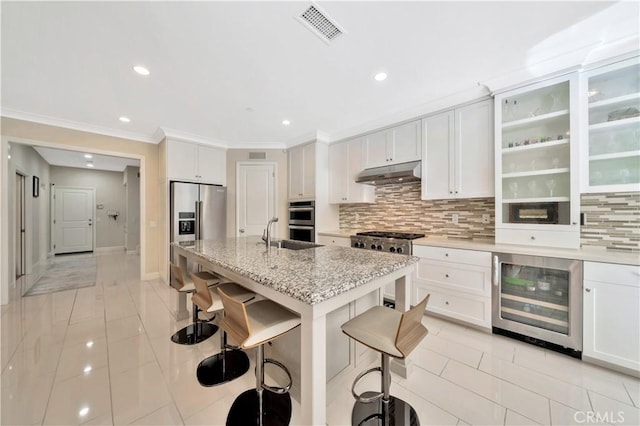 kitchen featuring wine cooler, a breakfast bar, light stone counters, and white cabinets