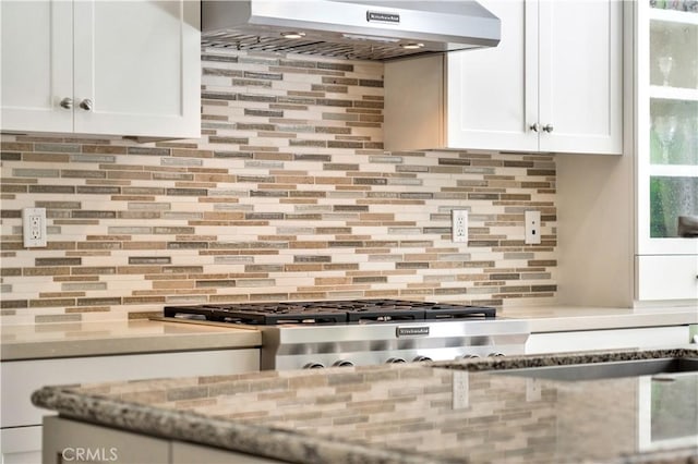 kitchen with extractor fan, tasteful backsplash, white cabinetry, range, and light stone countertops