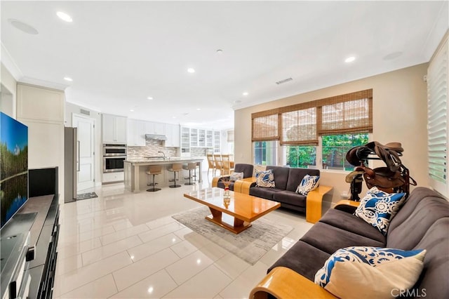 living room featuring sink, ornamental molding, and light tile patterned flooring