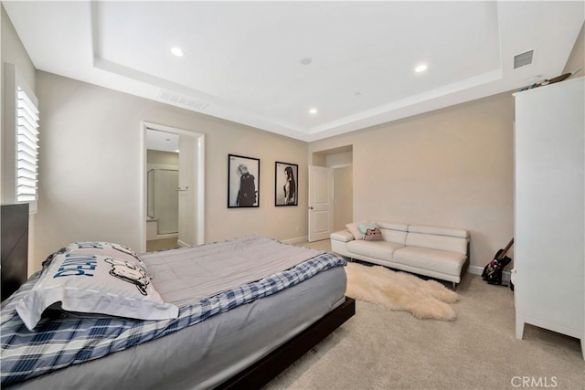 bedroom with a tray ceiling and light carpet