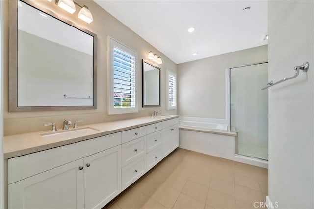 bathroom featuring a relaxing tiled tub, vanity, and tile patterned floors