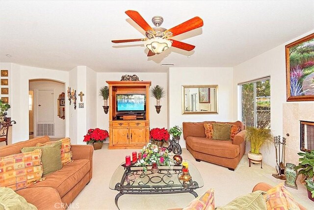 carpeted living room featuring ceiling fan and a high end fireplace