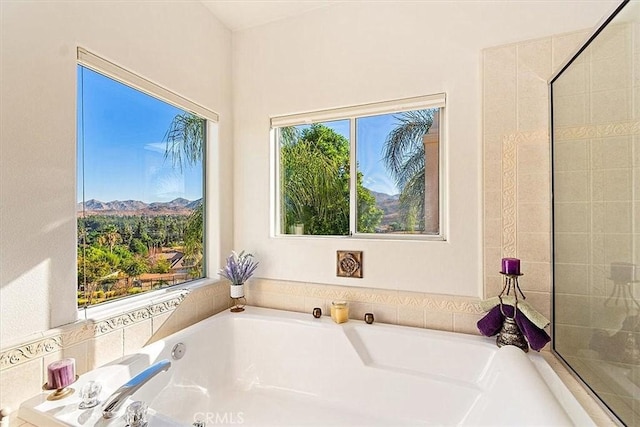 bathroom with a tub, a mountain view, and a healthy amount of sunlight