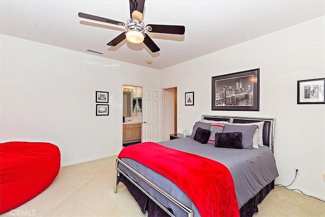 carpeted bedroom with ensuite bath and ceiling fan