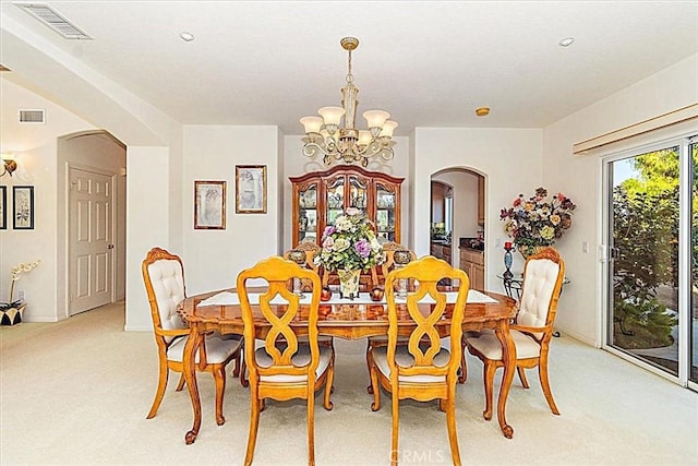 carpeted dining area with an inviting chandelier