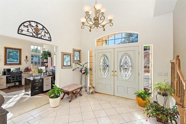 foyer entrance with french doors, a towering ceiling, light tile patterned floors, and a notable chandelier