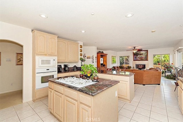 kitchen with light brown cabinetry, a kitchen island, a healthy amount of sunlight, and white appliances