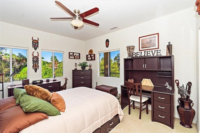 bedroom with multiple windows, light colored carpet, and ceiling fan