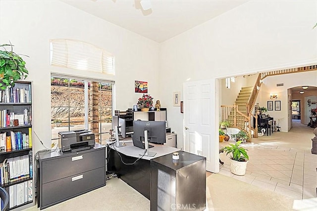 carpeted office with a high ceiling and ceiling fan