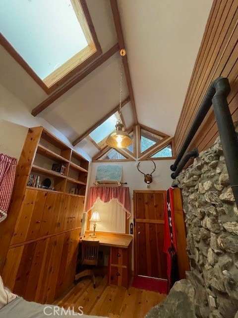 unfurnished bedroom with wood-type flooring, beamed ceiling, a skylight, and high vaulted ceiling