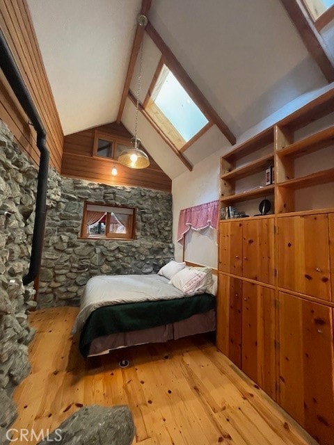 bedroom with beamed ceiling, a skylight, light wood-type flooring, and high vaulted ceiling