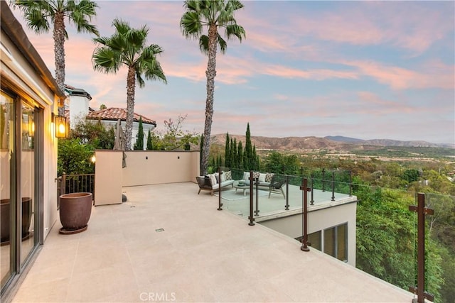 patio terrace at dusk with outdoor lounge area and a mountain view