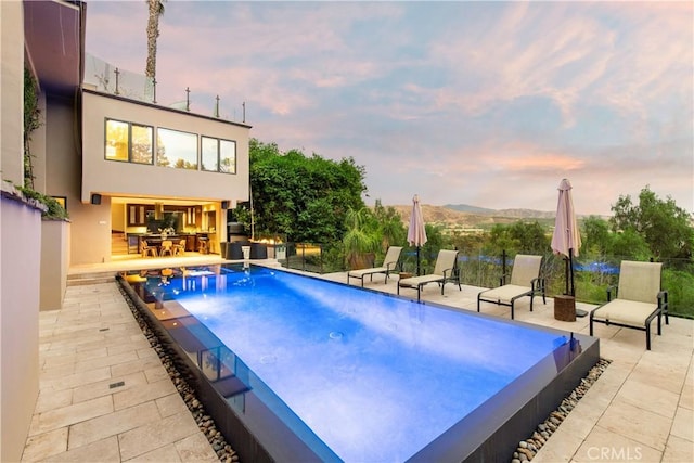 pool at dusk with a mountain view and a patio