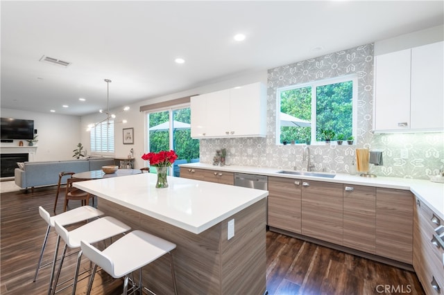 kitchen featuring sink, tasteful backsplash, white cabinetry, a breakfast bar, and dark hardwood / wood-style flooring