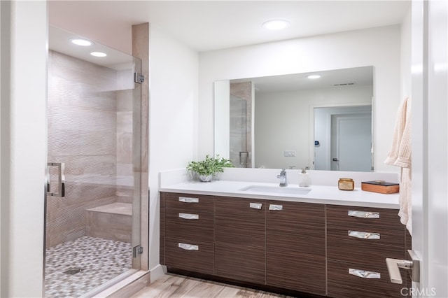 bathroom with wood-type flooring, a shower with door, and vanity