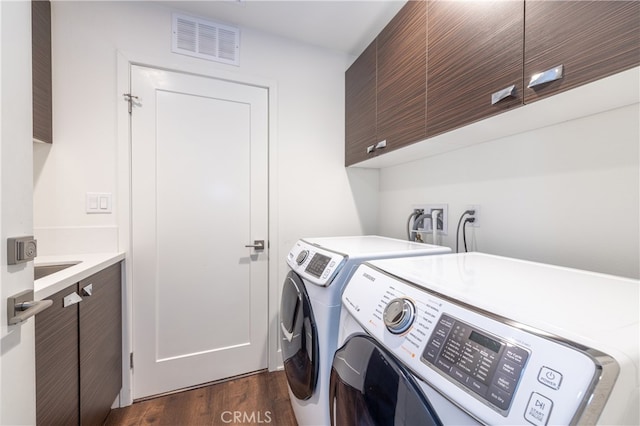 laundry room with cabinets, dark wood-type flooring, and washing machine and dryer