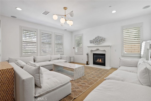 living room featuring a healthy amount of sunlight, light wood-type flooring, and an inviting chandelier