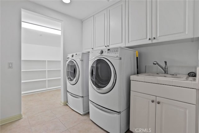 washroom with washing machine and dryer, sink, light tile patterned flooring, and cabinets