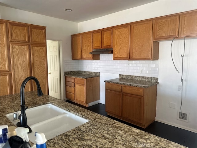 kitchen featuring dark stone countertops, sink, and decorative backsplash