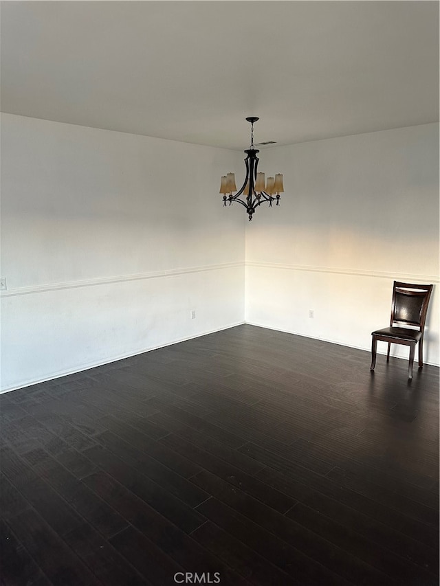 empty room featuring dark hardwood / wood-style floors and an inviting chandelier