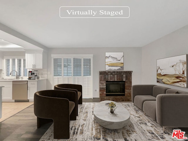 living room featuring a brick fireplace, sink, and a healthy amount of sunlight