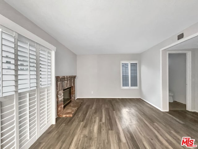 unfurnished living room with dark hardwood / wood-style floors and a brick fireplace