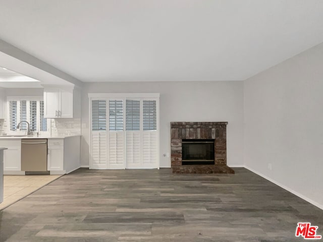 unfurnished living room with light wood-type flooring, a fireplace, and sink