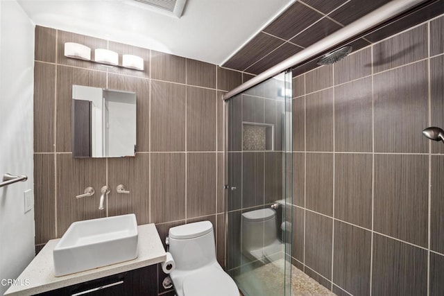 bathroom featuring an enclosed shower, vanity, toilet, and tile walls