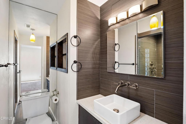 bathroom featuring vanity, toilet, tile walls, and a shower with shower door