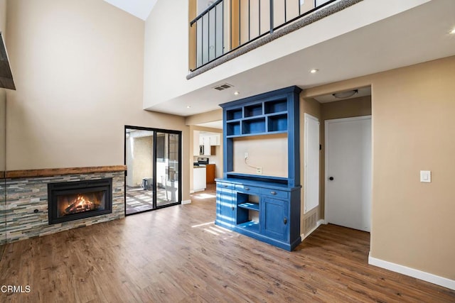 unfurnished living room with a fireplace, wood-type flooring, and a high ceiling