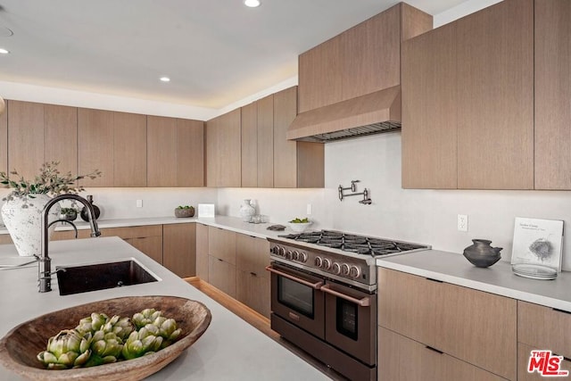 kitchen with light brown cabinets, double oven range, custom range hood, and sink